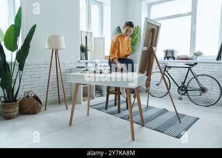 Schöne junge Frau, die Farben beim Zeichnen im Kunststudio mischt Stockfoto