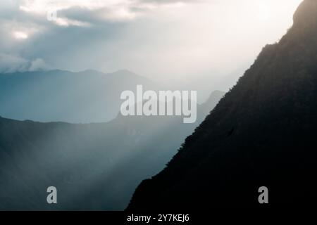 Eine ruhige Berglandschaft mit Sonnenstrahlen, die durch Wolken brechen und das nebelige Tal darunter hervorheben. Stockfoto