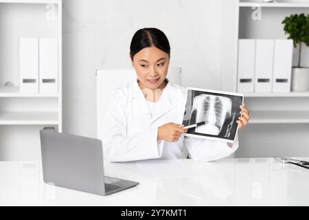 Ein Arzt untersucht eine Thoraxröntgenaufnahme, während er die Befunde in der Klinik bespricht Stockfoto