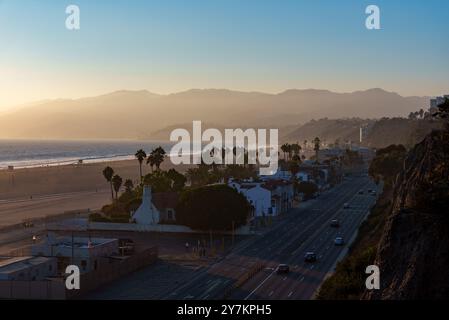 Ein atemberaubender Blick aus der Luft zeigt einen wunderschönen Strand entlang einer befahrenen Autobahn während eines malerischen Sonnenuntergangs, der den Himmel von Santa Monica übermalt Stockfoto
