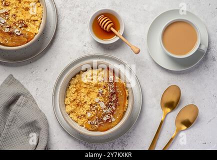 Lebensmittelfotografie von Hirsebrei mit karamelisierter Banane, Pekannuss, Nüssen, Kokosflocken, Chia, Leinsamen, Honig, Tee mit Mandelmilch Stockfoto