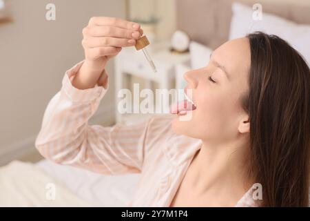 Junge Frau, die CBD-Öl im Schlafzimmer nimmt, Nahaufnahme Stockfoto