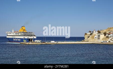 Fähre im Hafen mit Blick auf das Meer, im Hintergrund eine kleine Kirche auf einem Hügel unter klarem Himmel, Bluestar Chios Fähre, Pigadia, Stadt und Har Stockfoto