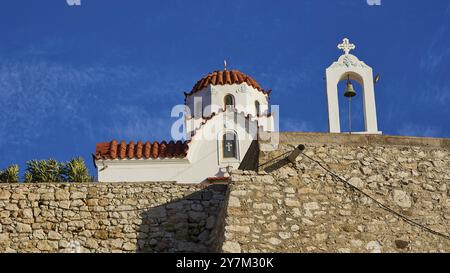 Eine kleine Kirche mit Glockenturm und Steinfassade unter einem klaren blauen Himmel, Panormitis Kirche, Pigadia, Stadt und Hafen, Pigadia Bay, Hauptstadt Karpatho Stockfoto