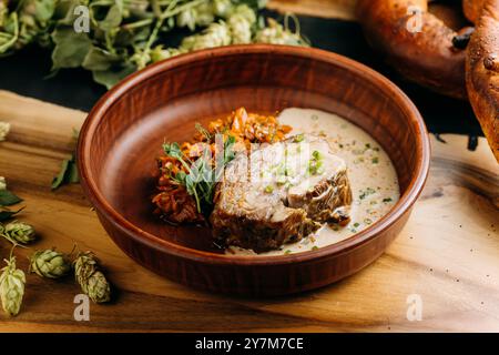 Köstliches langsam gekochtes Fleisch, serviert mit karamelisiertem Gemüse und cremiger Sauce in einer rustikalen Schüssel Stockfoto