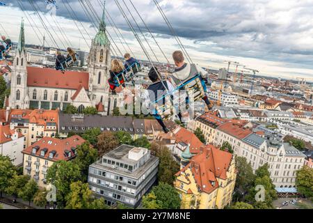 Wiesnbesucher genießen den Flug durch den Münchner Himmel, mit dem Kettenflieger Bayern Tower drehen sie sich in 90 Metern Höhe, Oktoberfest, München, September 2024 Deutschland, München, 30. September 2024, Wiesnbesucher genießt den Flug durch den Münchner Himmel, in 90 Metern Höhe haben sie einen wunderbaren Blick über die Stadt, vor ihnen liegt der Stadtteil Ludwigsvorstadt mit der Kirche St. Paul, der Kirchturm von St. Paul ist 97 Meter hoch, Kettenflieger Bayern Tower, 90 Meter hohes Kettenkarussell, Theresienwiese, Fahrgeschäft gehört Schausteller Egon Kaiser, Montagnachmittag, Himmel b Stockfoto