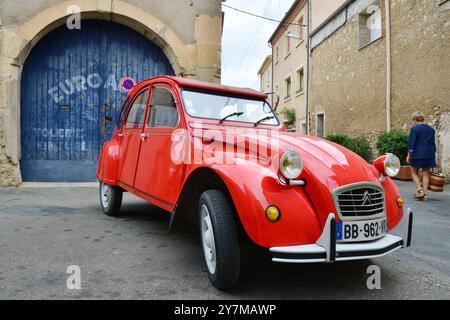 HERAULT (34). SAINT-CHINIAN. RED CITROEN CAR 2CV PARKTE VOR EINER GARAGE Stockfoto