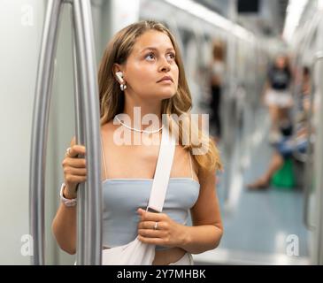 Ein junges Mädchen, das im Wagen steht, mit kabellosen Kopfhörern auf der Luft Stockfoto