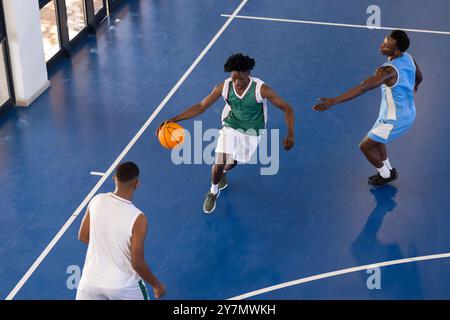 Basketball spielen, drei afroamerikanische Männer in Aktion auf dem Hallenplatz, Dribbeln und Verteidigen Stockfoto