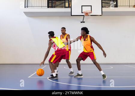 Basketball spielen, drei Athleten in Aktion auf dem Hallenplatz mit Ball Stockfoto