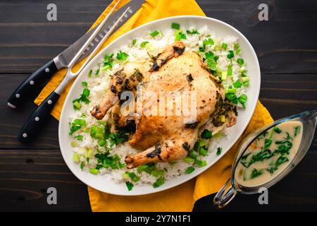 In Kokosnussmilch mit Zitronengras geröstetes Huhn über Reis: Ganzes Huhn serviert auf einer Platte mit Jasminreis, Zwiebeln und Koriander Stockfoto