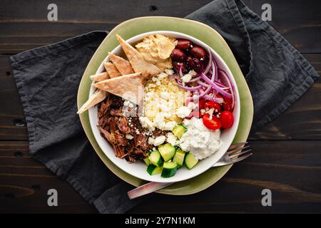 Gyro-Schüssel nach griechischer Art mit geriebenem Rindfleisch und Oregano: Couscous mit Tzatziki, Feta, schwarzen Oliven, Gurken, Traubentomaten, Hummus und Pita Stockfoto