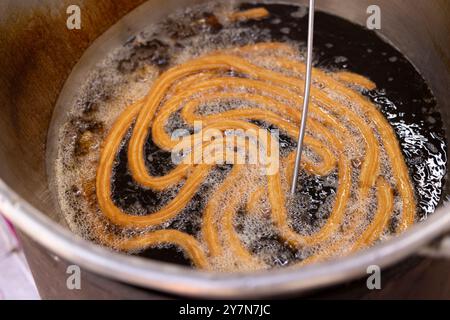 Churro-Teig Pommes in einem Topf heißes Öl. Stockfoto