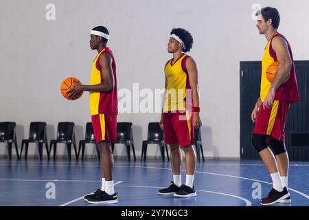 Basketball spielen, drei Männer in Sportuniformen halten Basketbälle auf dem Platz Stockfoto