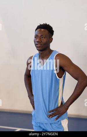 Basketballspieler in blauem Trikot, der auf dem Platz steht und entschlossen aussieht Stockfoto