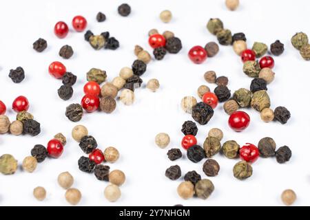 Rote, grüne, weiße und schwarze Pfefferkörner auf weißem Hintergrund. Stockfoto