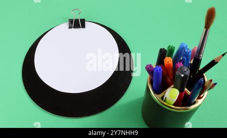 Leere Seite im Kopierbereich des Bürotischs mit grünem Hintergrund und Stifthalter. Stockfoto