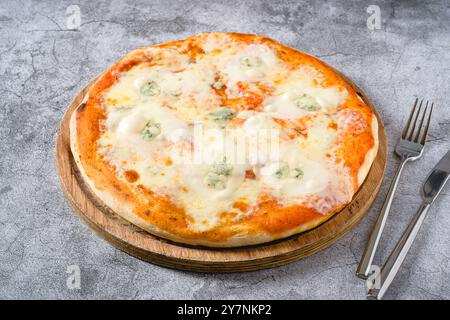 4 neapolitanische Käse-Pizza auf hölzernem Schneidebrett auf Steintisch Stockfoto