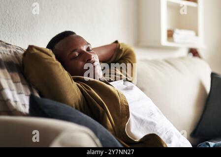 Schwarzer Mann, Schlaf- und Couch zum Ausruhen zu Hause, Ruhe und komfortables Wohnzimmer zum Träumen. Mann, faules Wochenende und chillt auf dem Sofa Stockfoto