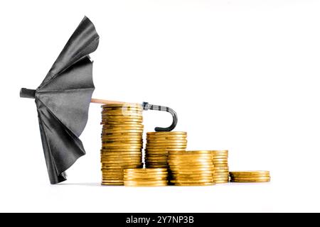 Schwarzer Spielzeugschirm, der auf weißen Münzstapeln platziert ist und finanzielle Absicherung, Risikomanagement und Sparstrategien im persönlichen bereich darstellt Stockfoto