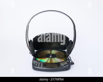 Nahaufnahme des CD-Players mit offenem Deckel und goldener CD-Innenseite und Kopfhörern auf weißem Hintergrund. Stockfoto