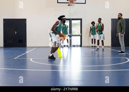 Basketball üben, Spieler dribbeln Ball um Kegel im Schulgymnasium Stockfoto