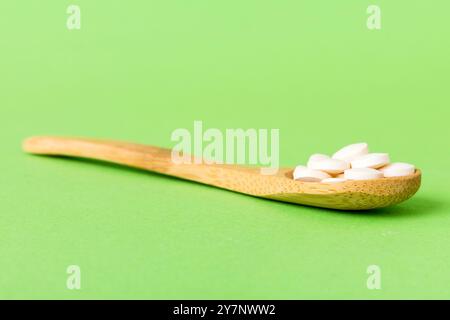 Haufen weißer Pillen auf farbigem Hintergrund. Tabletten auf einem Tisch verstreut. Haufen roter weicher Gelatinekapsel. Vitamine und Nahrungsergänzungsmittel Konzept. Stockfoto