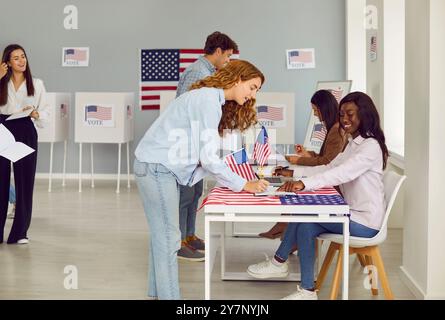 Seitliches Porträt eines jungen Mädchens, das sich am Wahltag mit amerikanischen Fahnen am Wahllokal anmeldet Stockfoto