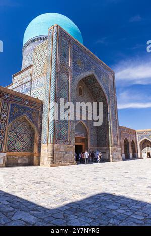 Samarkand, Usbekistan - 25. März 2024: Touristen besuchen die Tilya-Kori Madrasah an einem sonnigen Tag, vertikales Foto Stockfoto