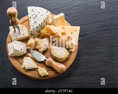 Käseplatte mit verschiedenen Käsesorten auf grauem Graphit-Tisch von oben. Stockfoto