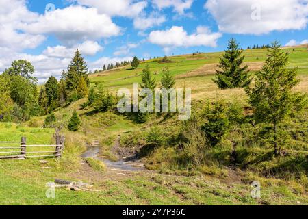 Ländliche Landschaft in den Bergen. Sonniger Herbsttag. karpatenlandschaft der ukraine. Landschaft mit Heuhaufen und Holzzaun. Flauschige Wolken am Himmel Stockfoto