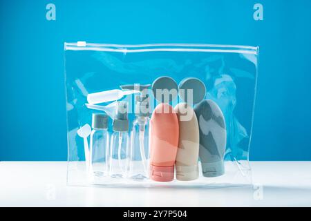 Transparente Kulturtasche mit verschiedenen Behältern in Reisegröße auf hellblauem Hintergrund Stockfoto