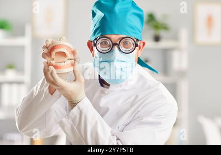 Lustiger Mann Arzt Zahnarzt, der in die Kamera blickt und Kiefer hält, die in der Zahnklinik stehen. Stockfoto