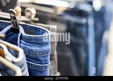 Jeans oder Jeans (Hosen) hängen an einem Kleiderbügel im Einkaufszentrum. Kollektion von Modeartikeln im Bekleidungsgeschäft zum Verkauf. Textilindustrie. Blau grau und b Stockfoto