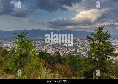 Dramatisches Stadtpanorama mit Blick auf grüne Hügel Stockfoto