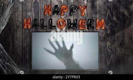 Schatten von Werwolfhänden mit Pelz und schwarzen Klauen auf dem Bildschirm mit Happy Halloween Ballon Text auf hölzernem Hintergrund. Gruselige Klaue des Werwolfs, wolfman Stockfoto