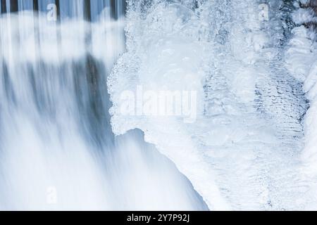 Der Wasserfall in Schweden ist von wunderschönen Eisformationen umgeben und zeigt die atemberaubende Schönheit des Winters. Der Wasserfluss steht im Gegensatz zum Stockfoto