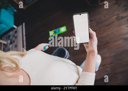 Zugeschnittenes Foto von Dame tragen weißes Hemd, das tägliche Putzen macht und modernes Gerät leerem Raum im Haus hält Stockfoto