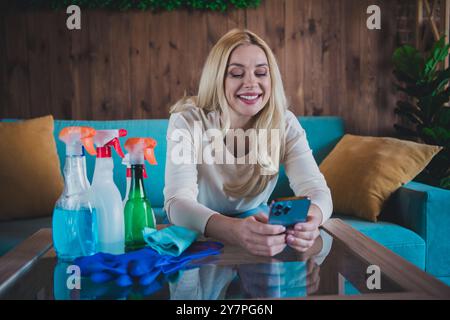 Foto von entzückender süßer Dame tragen weißes Hemd, das tägliche Putzen macht, modernes Gerät im Haus des Zimmers chatten Stockfoto