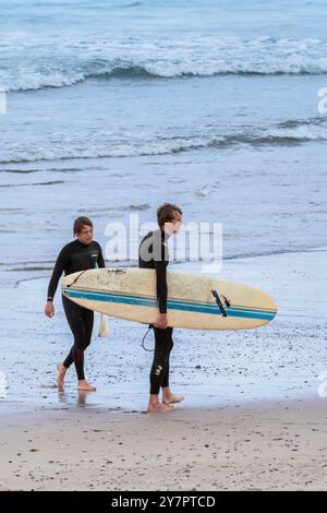 Zwei männliche Surfer mit Surfbrettern am Fistral Beach in Newquay in Cornwall, Großbritannien. Stockfoto