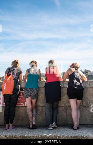 Vier Frauen stehen und blicken über die Hafenmauer im Newquay Harbour Harbor in Newquay in Cornwall in Großbritannien. Stockfoto