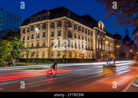 Abendlicher Stadtverkehr, Cecilienallee, Bundesautobahn B1, Radfahrer wartet auf einer Linkskurve, um seine Reise fortzusetzen, Gebäude der Düsseldor Stockfoto