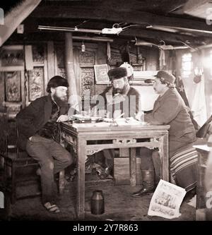 Yangtse-Fluss, China. Foto von John Thomson, 1871. Das Innere einer Hütte mit drei europäischen Männern, die um einen Tisch sitzen, darunter John Thomson (Mitte). Ferngläser auf dem Tisch, eine Ausgabe von Harper's Weekly im Vordergrund, Appleton's Journal an der Wand dahinter. Zwei Winchester-Gewehre hängen von der Decke, eine andere am Fenster rechts. Stockfoto