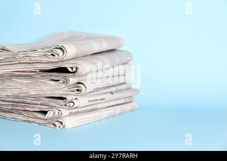 Stapel Zeitungen auf hellblauem Hintergrund, Platz für Text Stockfoto