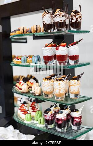 Verschiedene Arten von süßen Desserts, Mousse. Dessertbuffet mit Mousse aus weißer und dunkler Schokolade mit Früchten in einem Glas Stockfoto