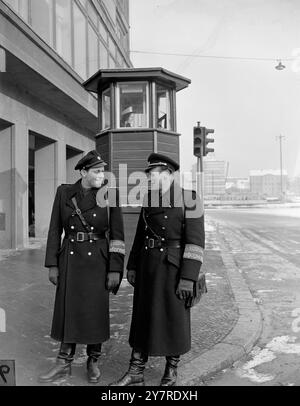 OST-BERLIN BEREITET SICH AUF DIE BIG-FOUR-KONFERENZ VOR. 1.24.54. Auch die Ost-Berliner Polizei fungiert als Führer und Dolmetscher für Besucher der Big Four Konferenz der Stadt. I.N.P. Foto zeigt: Polizistin in Verkehrskontrollbox am Alexanderplatz im sowjetischen Sektor, obwohl kein Verkehr sichtbar ist. Zwei „Vopos“ (Volkspolizei), ostdeutsche Polizeibeamte mit Guide-Dolmetscher-Armbändern für die Besucher der Big Four Conference. Internationales Männerfoto von Joe Waldorf. Stockfoto