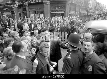 LONDON: Zwei Polizisten versuchen heute, Menschenmassen in der Brewer Street Soho aufzuhalten, wo der Amerikaner Muhammad Ali (Vordergrundkamera), der Boxweltmeister im Schwergewicht, versuchte, eine Pressekonferenz zu verlassen, die er in Isows Restaurant hielt. Clay, der am 21. Mai in Highbury den britischen und Empire-Schwergewichtsmeister Henry Cooper trifft, sagte der Pressekonferenz, dass er alles tun werde, um ein würdiger Champion zu werden. Der inzwischen sanfte, milde und reife Champion dankte allen Beteiligten, dass er ihm die nötige Zeit gegeben hatte, um Großbritannien zu besuchen und sich gegen Cooper für den Cha zu verteidigen Stockfoto