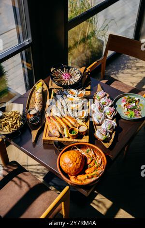 Am Restauranttisch werden Meeresfrüchte mit verschiedenen gegrillten Fischsorten, Austern, Garnelen und Vorspeisen serviert Stockfoto