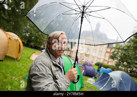 PRODUKTION - 01. Oktober 2024, Nordrhein-Westfalen, Münster: Axel Prahl (Oberinspektor Frank Thiel), Schauspieler, steht zwischen Zelten im Park hinter der Burg am Set des Münsterer Tatorts. Die neue Episode „Ich gestehe“ (AT) befasst sich mit dem Wohnungsmangel bei Studenten. Foto: Rolf Vennenbernd/dpa Stockfoto