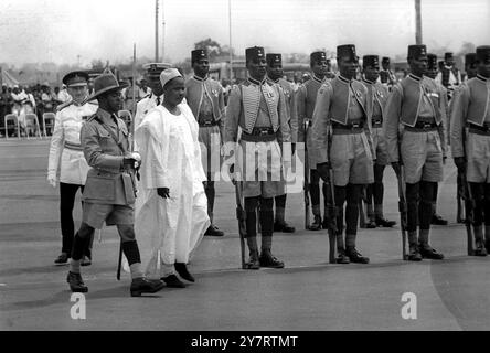 EHRENGARDE FÜR AFRIKANISCHE MINISTER, die die Ehrengarde bei seiner Ankunft hier für die Konferenz der afrikanischen Minister in Lagos inspizieren sehen, ist der Präsident der Republik Kamerun, Amadou Ahidjo (in weißen Gewändern), der hinter sich geht, (links) ist Generalmajor Norman Foster, Kommandeur der nigerianischen Armee. Die Konferenz über die afrikanische Einheit wurde heute hier eröffnet. 25. Januar 1962 Stockfoto